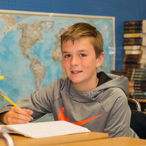 Elementary student sitting at deck with world map in background