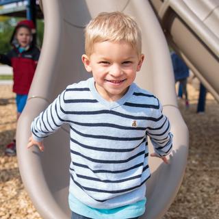 4K boy on playground at bottom of slide